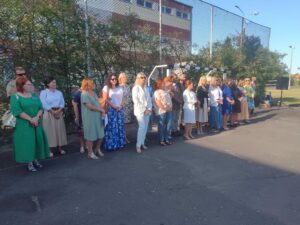 Widok całej rady pedagogicznej stojącej na boisku szkolnym