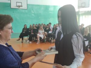 Wychowawca wręcza świadectwo i nagrodę swojemu uczniowi
