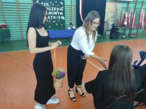 Uczniowie klas trzecich wręczają upominki absolwentom