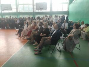 Widok stojących uczniów i siedzących nauczycieli