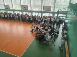 Widok stojących uczniów i siedzących nauczycieli