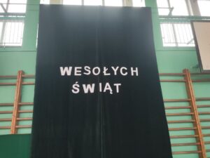 Widok rozwieszonej dużej zielonej tkaniny z napisem „WESOŁYCH ŚWIĄT”