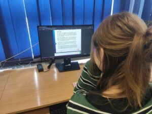 Zdjęcie uczennicy przeglądającej na komputerze materiały na temat zagrożeń internetowych.